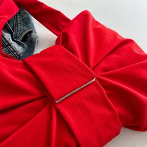Detailopname van de rode nylon draagtas met grote strikknoop en getextureerde stofafwerking