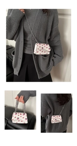 Detail view of mini shoulder bag with red lip print patterns and silver metal chain strap