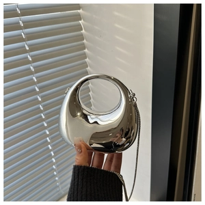 Detail of silver mirror metal clutch with circular cutout handle and fine chain strap