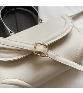 Detail der verstellbaren Riemen mit goldener Schnalle an cremefarbener Steppledertasche