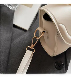 Nahaufnahme der goldenen Metallschnalle und Lederstruktur der retro cremefarbenen Tasche