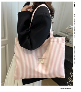 Detail of a large pink and white striped tote bag showing woven texture and text patch