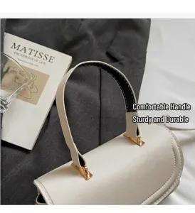 Detailansicht einer weißen Lederhandtasche mit Rundgriff und goldenen Metallschnallen
