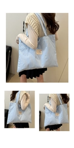 Detail of blue and white striped canvas tote bag with wide strap and text label