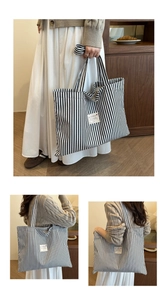 Detail view of large capacity striped canvas tote bag with woven label used as shoulder bag