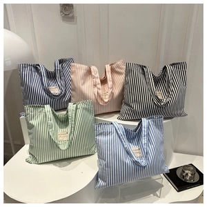 Detailed close-up showing five colors of striped canvas tote bags on a white display stand
