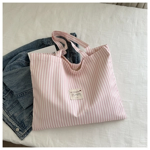 Detail of pink and white striped canvas tote bag with a minimalist quote patch on the front