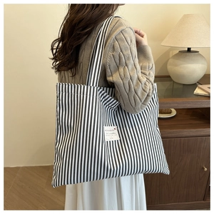 Detail view of a large striped canvas tote bag with shoulder straps for daily commuting