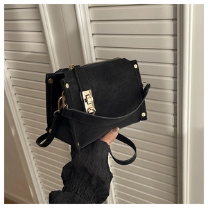 Détail du sac bandoulière en daim noir avec boucle dorée et rivets décoratifs