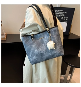 Detail van grijze marmeren tote bag met zwarte riemen en een zachte pluche bal hanger