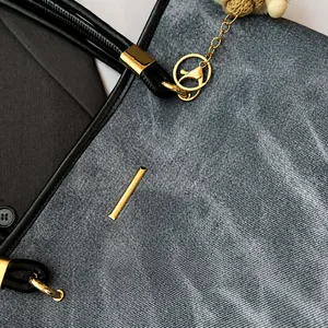 Detail of washed grey denim fabric with black leather trim and gold metal hardware