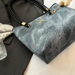 Detailed shot of dark grey tote with leather handles and white wool charm on a suit