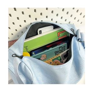 Interior espacioso del bolso bandolera de lona azul con libros y tableta organizada