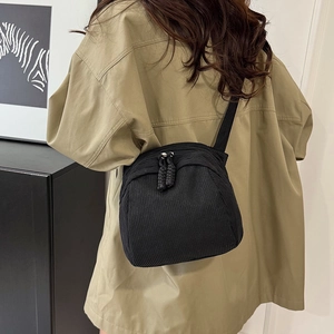 Minimalist black corduroy shell bag with pleated texture and adjustable shoulder strap