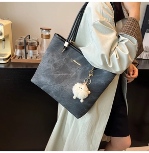 Detail of grey marble pattern tote bag with black handles and white pompom charm
