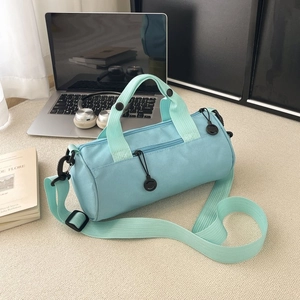 Minimalist light blue cylinder fitness bag with green straps in a clean indoor setting