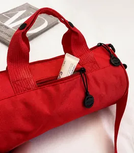 Detail view of red cylindrical gym bag with durable fabric, handles and side zipper pocket