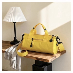 Detail of a bright yellow barrel sports bag showing nylon fabric and matching straps