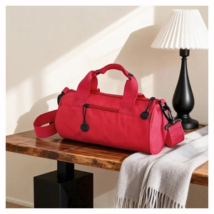 Detail of red cylindrical duffel bag with zipper on a walnut table for travel and gym