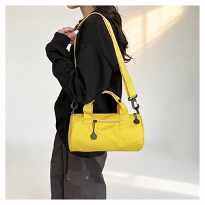Detail of yellow cylindrical duffel bag with black zipper and smiley charm for travel