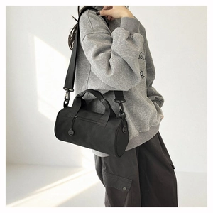 Detail view of the black nylon cylindrical duffel bag with wide adjustable shoulder straps