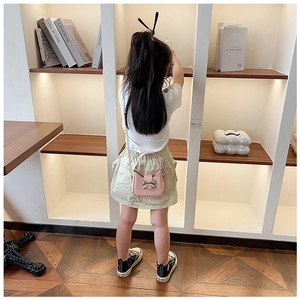Dettaglio di una mini borsa a tracolla rosa per bambina con un fiocco in metallo argento