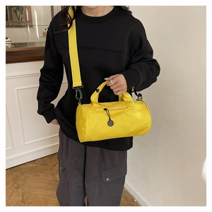 Detailed view of yellow cylindrical duffel bag with black zippers and durable shoulder straps