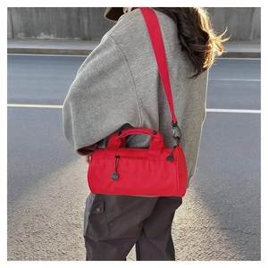 Detail view of red cylindrical fitness duffel bag with woven straps and black hardware