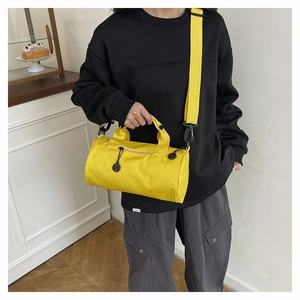 Détail d'un sac polochon jaune en toile avec poignées tissées et fermetures éclair noires