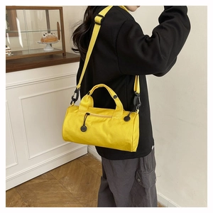 Detail view of a vibrant yellow cylinder duffel bag with black adjustable straps and handles