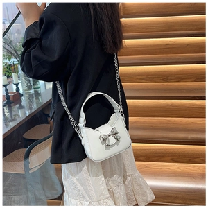 Mini borsa bianca da bambina con fiocco argento, indossata da una modella