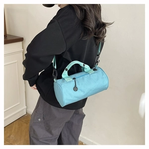 Close-up of light blue cylinder gym bag with mint green handles and detachable strap