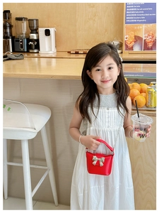 Dettaglio mini borsa in pelle rossa con fiocco argento e catena in metallo bimba