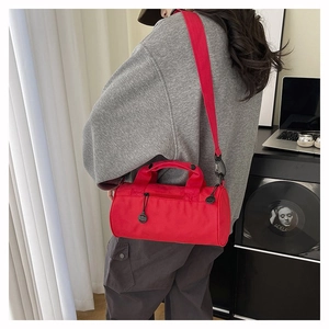 Detail of red cylindrical sports duffel bag showing back view on model with shoulder strap