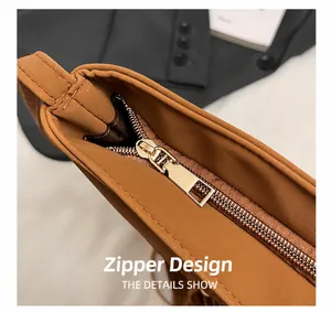 Détail de la fermeture éclair dorée et du cuir synthétique marron du sac à bandoulière