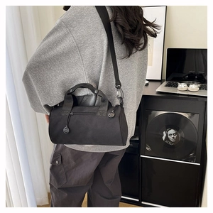 Male model carrying a black cylindrical sports duffel bag in a minimalist modern interior