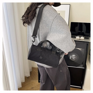 Detail of the black cylindrical gym bag with adjustable shoulder strap and dual handles