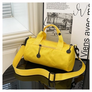 Detail of a bright yellow canvas cylindrical gym bag with durable straps and side handle