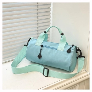 Detail of light blue cylinder duffel bag with woven handles and smiley zipper charm