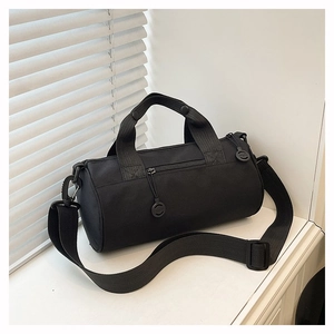 Detail of minimalist black cylinder gym bag with adjustable strap and side pocket