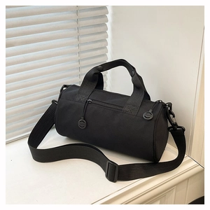 Close-up of black cylindrical sports bag with nylon shoulder strap and circular zipper pull
