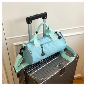 Detail of mint green duffel bag with black hardware and adjustable shoulder strap
