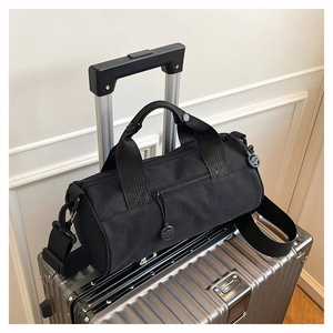 Detail of black cylinder gym bag showing the dual handles and adjustable shoulder strap