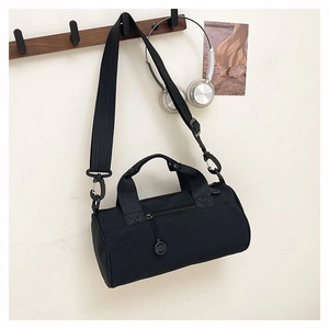 Detail of a black cylinder travel bag featuring adjustable strap and circular zipper pull