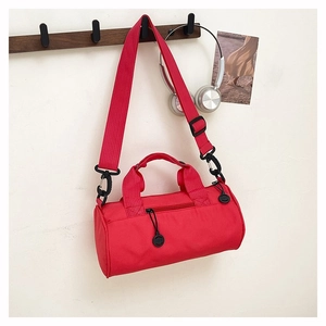 Red cylindrical sports bag hanging on hook with headphones and lifestyle decor