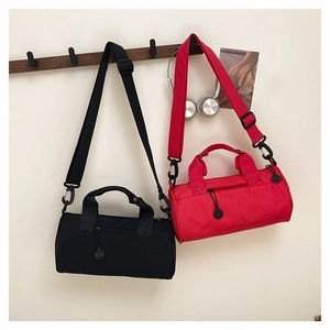 Detail of minimalist cylinder gym bags in black and red hanging on wooden wall hooks
