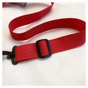 Detail of red nylon strap with black adjustable buckle and swivel hook for travel bags