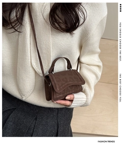 Dettaglio mini borsa in finta pelle scamosciata marrone con manico e tracolla su una modella