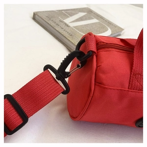 Detail of red cylindrical sports bag with matching nylon strap and secure black buckles