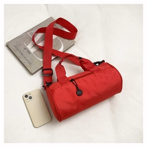 Mini red cylindrical gym bag shown with phone and book to demonstrate portable size